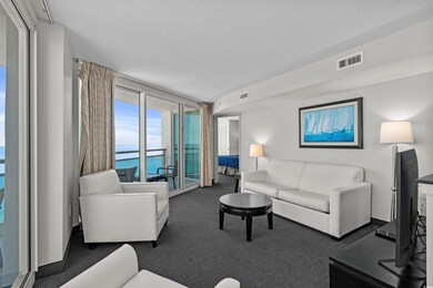 Living room with a textured ceiling, a wall of win