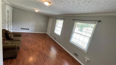 Living room featuring a textured ceiling, crown molding, and wood finished floors