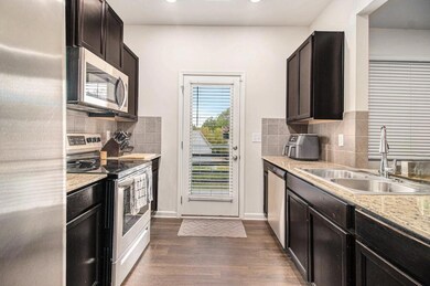 The Kitchen features Granite Countertops, Stainless Steel Appliances, Dark Wood Cabinetry, and a convenient view to the Living Room.