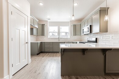 Kitchen featuring gray cabinets, a breakfast bar, a peninsula, decorative light fixtures, and recessed lighting