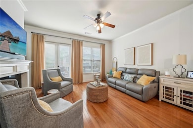 Living room with ceiling fan, ornamental molding, and wood finished floors