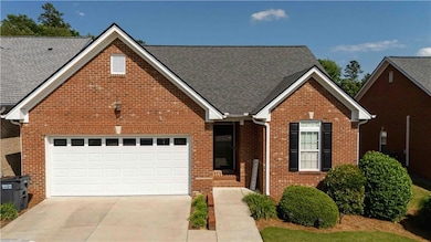Traditional-style home with driveway, brick siding, a garage, and roof with shingles