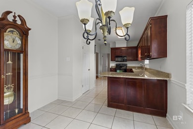 Kitchen with light stone countertops, a peninsula, ornamental molding, light tile patterned flooring, and black appliances