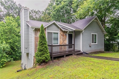 Single story home with a chimney, a front lawn, a wooden deck, and roof with shingles