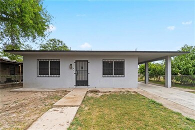 View of front of property with driveway, a front yard, an attached carport, stucco siding, and fence