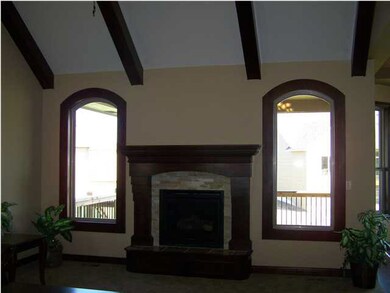 Custom fireplace and vaulted beamed ceiling in liv
