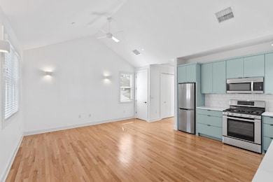 Kitchen featuring light countertops, appliances with stainless steel finishes, blue cabinets, backsplash, and light wood-style floors