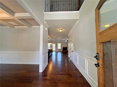 Foyer entrance featuring ornamental molding, dark wood-style floors, a decorative wall, a wainscoted wall, and beam ceiling