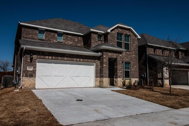 View of front of property featuring central air condition unit and a garage