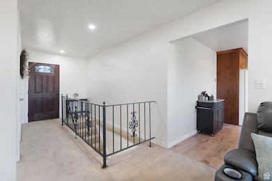 Hall featuring an upstairs landing, recessed lighting, light carpet, and light wood finished floors