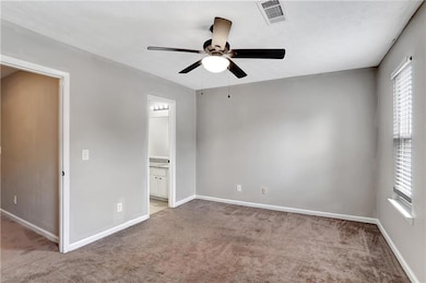 Unfurnished bedroom with carpet flooring, connected bathroom, and ceiling fan