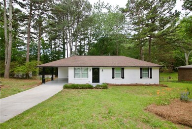 Ranch-style home featuring driveway, a front lawn, a carport, and roof with shingles