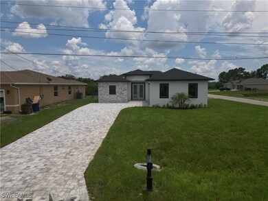 Prairie-style home featuring decorative driveway, stucco siding, a front lawn, and french doors