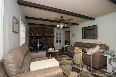 Living area featuring ceiling fan, beam ceiling, and a textured ceiling