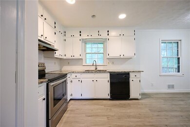 Kitchen featuring dishwasher, stainless steel range with electric stovetop, a sink, under cabinet range hood, and tasteful backsplash