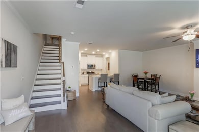 Living area with ornamental molding, stairs, a ceiling fan, dark wood-style floors, and recessed lighting