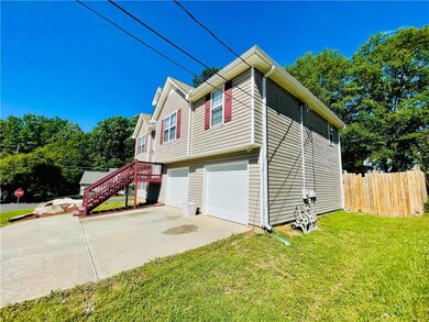 View of side of property with an attached garage, driveway, and stairway