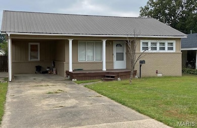 View of front of home with brick siding, an attached carport, a front yard, and covered porch