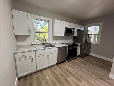 Kitchen featuring sink, light wood-type flooring, white cabinetry, appliances with stainless steel finishes, and light stone counters