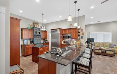Kitchen featuring a peninsula, brown cabinets, a breakfast bar, dark stone countertops, and recessed lighting