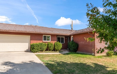Ranch-style home with concrete driveway, a tiled roof, a front lawn, brick siding, and an attached garage
