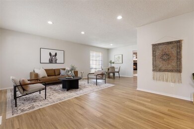 Living room featuring a textured ceiling, light wood-style flooring, recessed lighting, and a warm lit fireplace