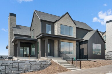 View of front of house with stone siding, roof with shingles, a sunroom, and a chimney