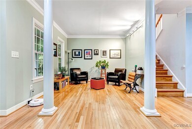 Sitting room with light wood-type flooring, ornate columns, and crown molding