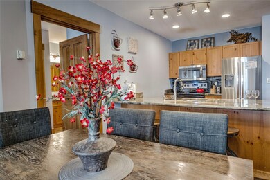 Kitchen featuring stainless steel appliances, a peninsula with light stone granite countertops