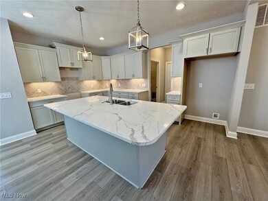 Kitchen with a center island with sink, backsplash, quartz counters, and recessed lighting