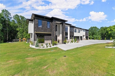 View of front of house with stone siding, a front yard, central AC, a playground, and stucco siding