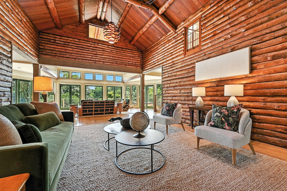 The residence sits on a 1.7-acre site on Luce Creek in Annapolis, Maryland. Above: Floor-to-ceiling windows connect the wood-walled living room to the outdoors. (Jeff Jackson)