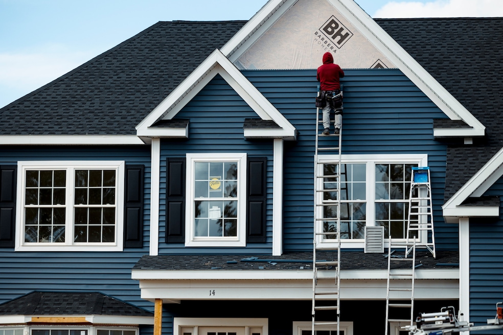 A worker installs siding on a home under construction in Loudonville, New York. (Angus Mordant/Bloomberg via Getty Images)