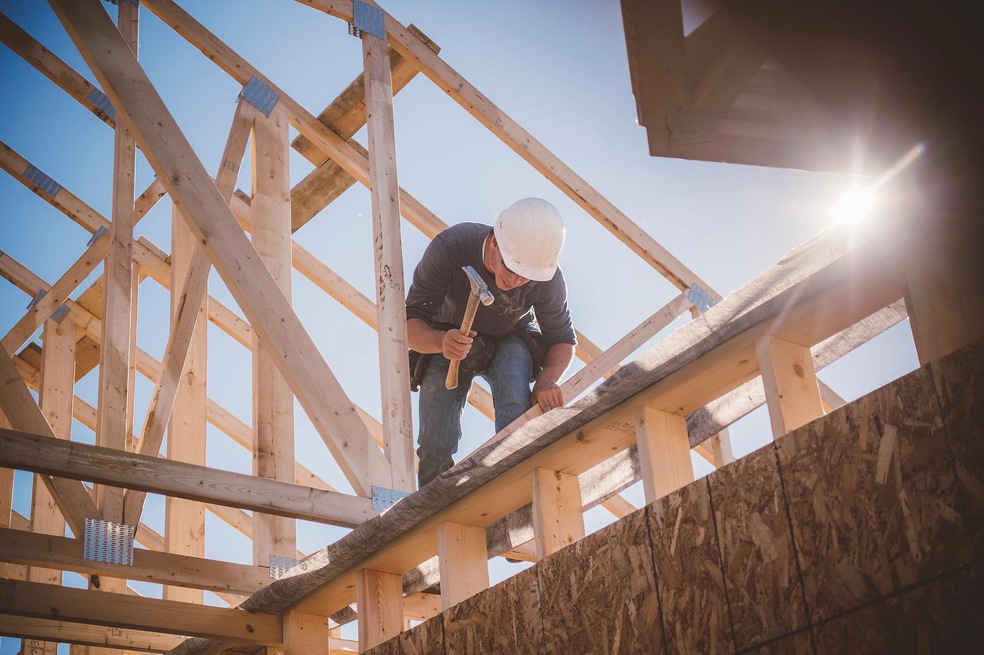 Builder working on rooftop frame of building. (Getty Images/Image Source)