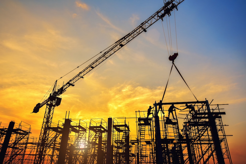 Silhouette of construction workers pouring a concrete column on scaffolding at a construction site. (Getty Images)