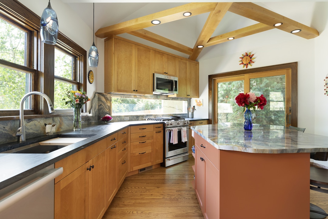 This kitchen remodel from Otogawa-Anschel Design Build uses warm wood cabinetry and a natural-look stone with plenty of natural light to bring the outdoors in. (Spacecrafting)